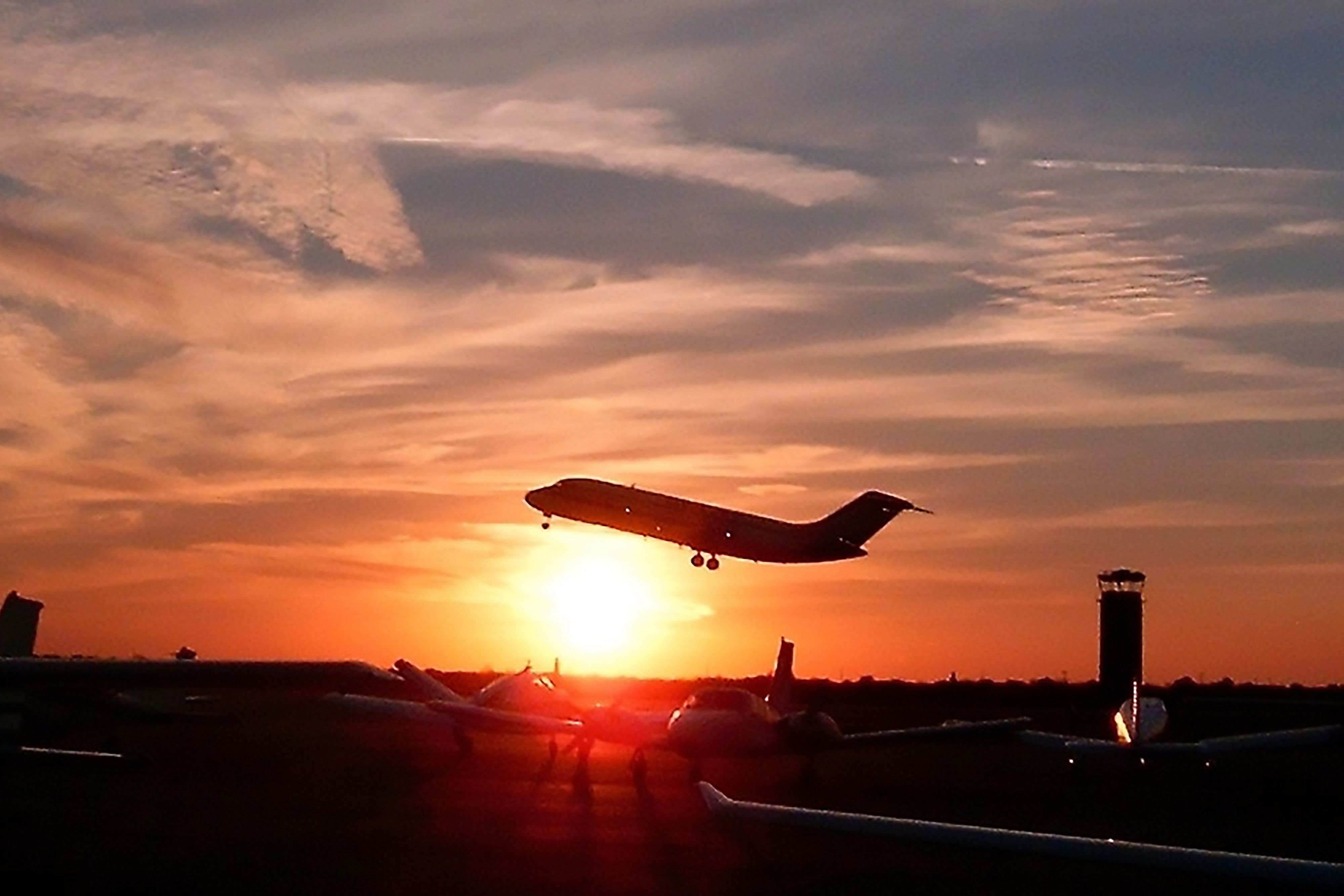 Silhouette of plane taking off at sunset