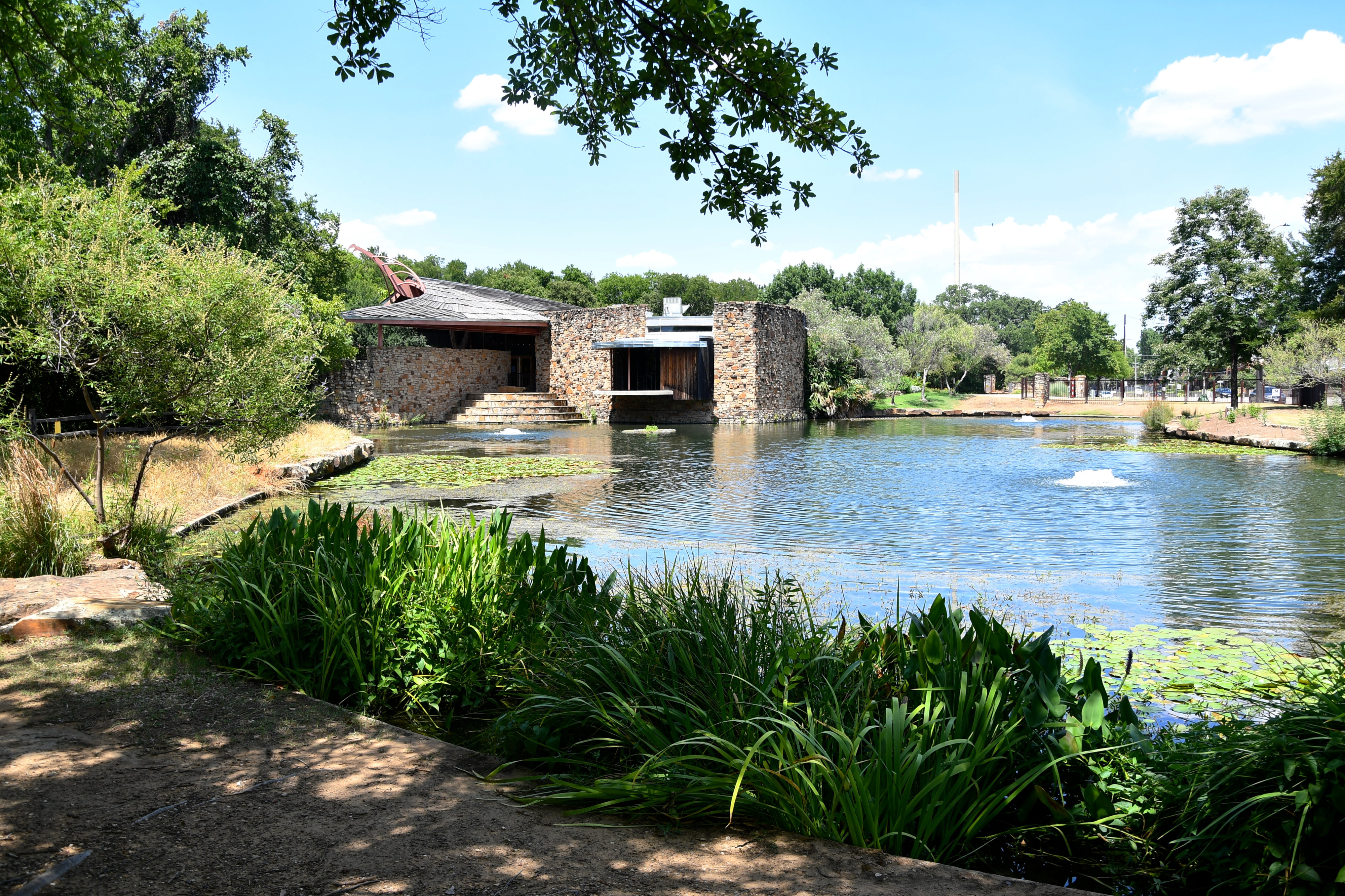 Brick building with a pond and water feature, plants in the foreground