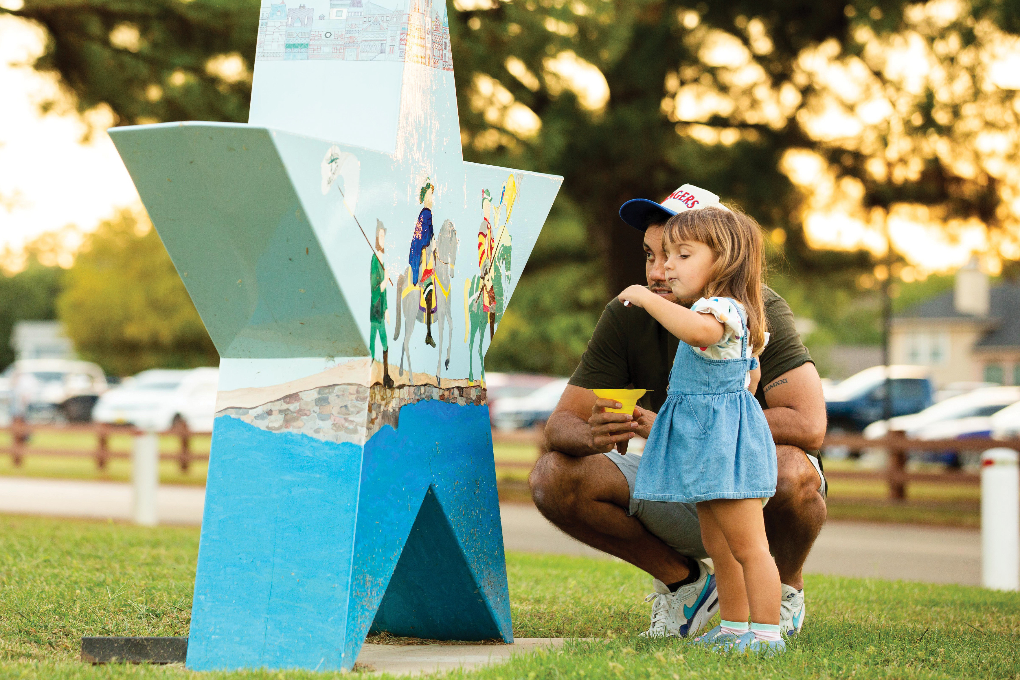 Man and child observing a star-shaped sculpture with painting on it